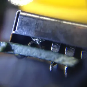 A close-up photo taken edge-on showing two pins coming off of a ROM chip and criss-crossing to effectively create a different pinout to the PCB.