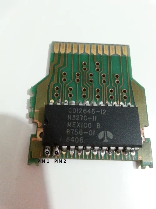 A photo of the same Pac-Man PCB and ROM chip that has the two pins in question marked with text to highlight their location.